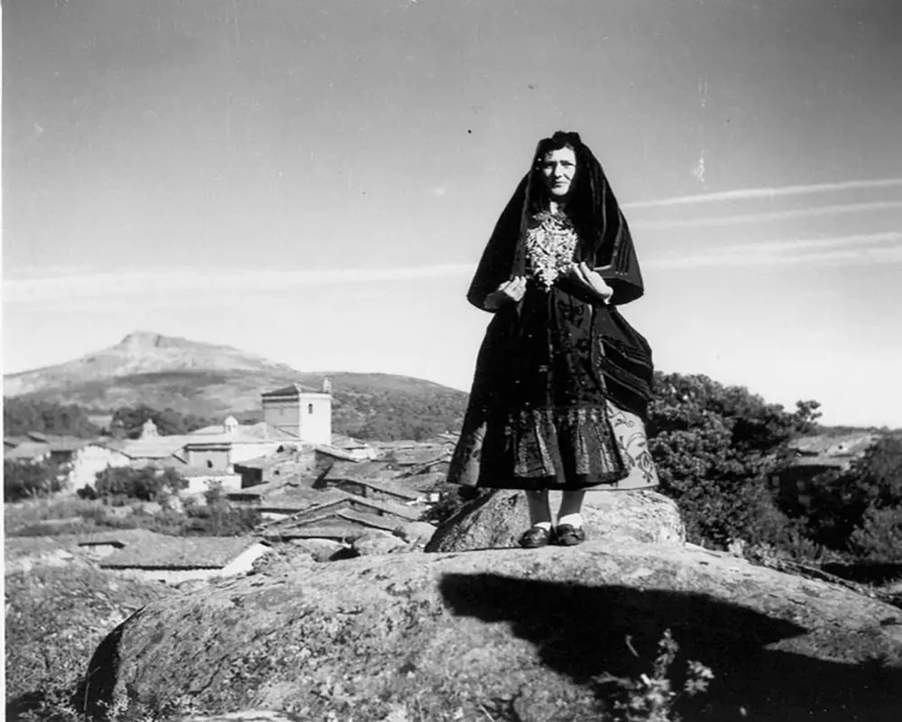 Foto de señora sobre peñas con el pueblo al fondo